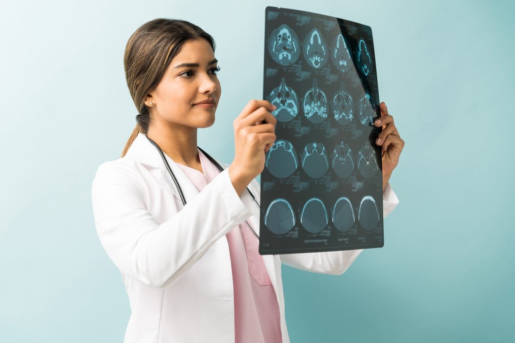 beautiful female doctor examining xray while standing studio