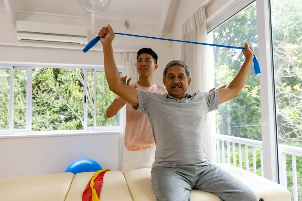 happy diverse male physiotherapist advising senior male patient using exercise band physiotherapy healthcare wellbeing senior lifestyle unaltered