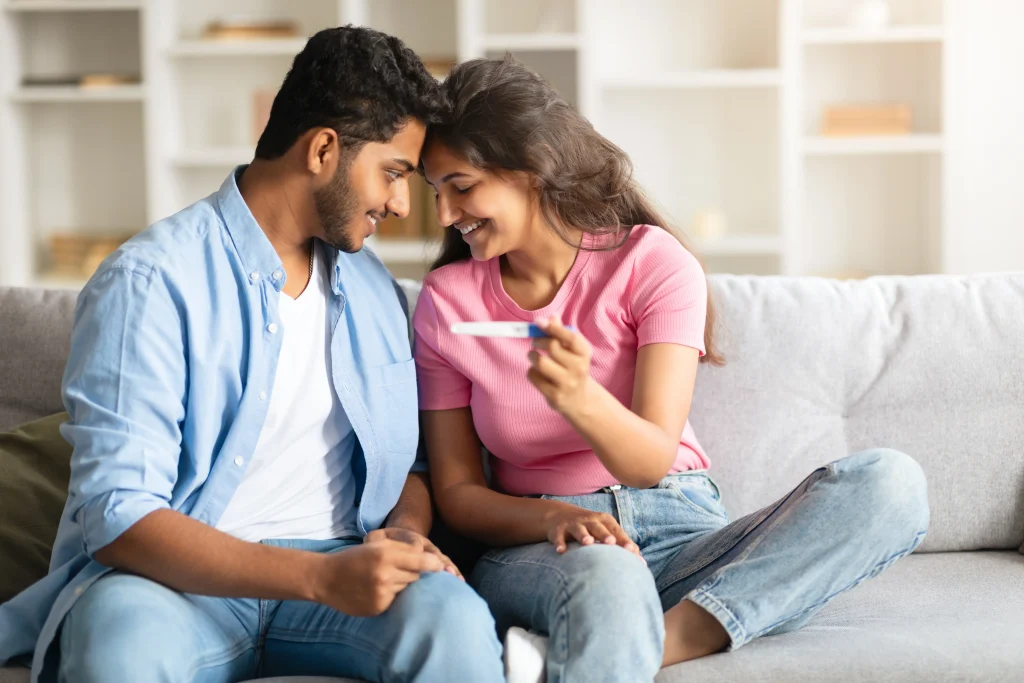 indian couple smiling with positive pregnancy test 1