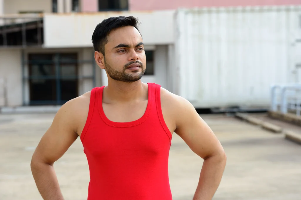 young man looking away while standing against built structure